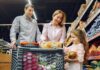 A family shopping together in a grocery store, with a child holding food items