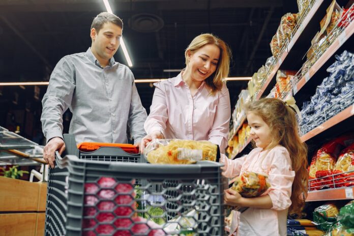 A family shopping together in a grocery store, with a child holding food items