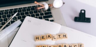 Scrabble tiles spelling 'HEALTH INSURANCE' on a planner