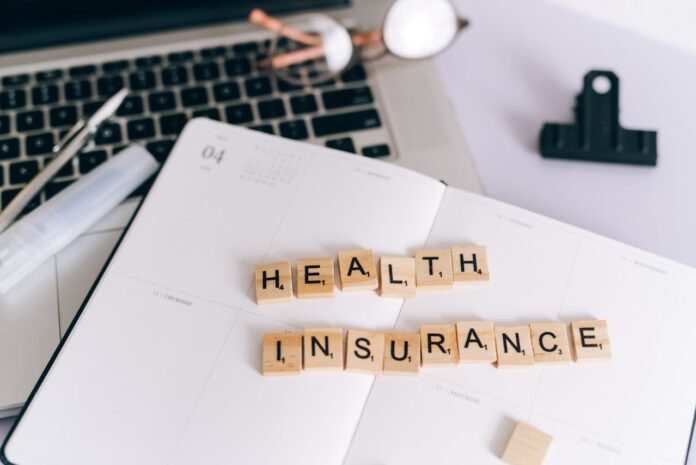 Scrabble tiles spelling 'HEALTH INSURANCE' on a planner