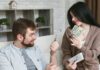 A couple sitting on a couch, discussing money and holding cash and a receipt